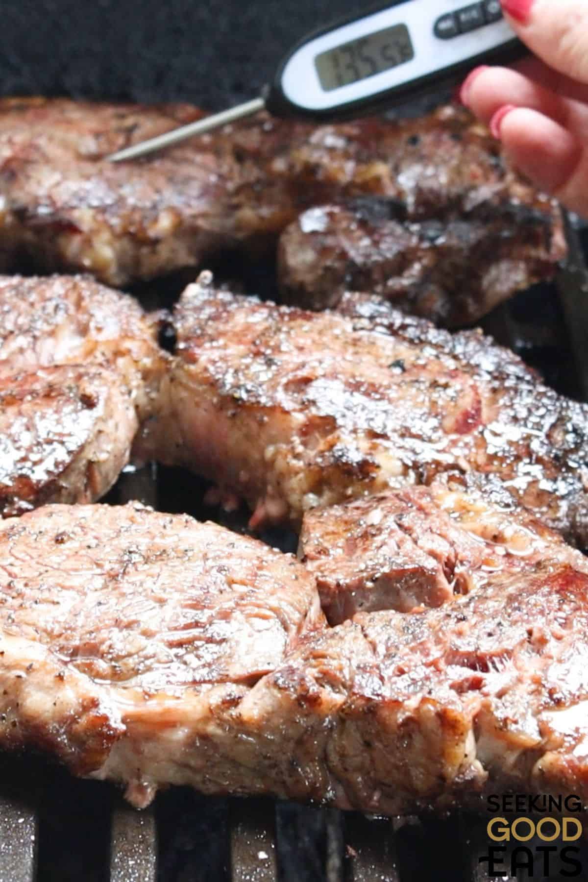 Juicy ribeye steaks being cooked on a grill.