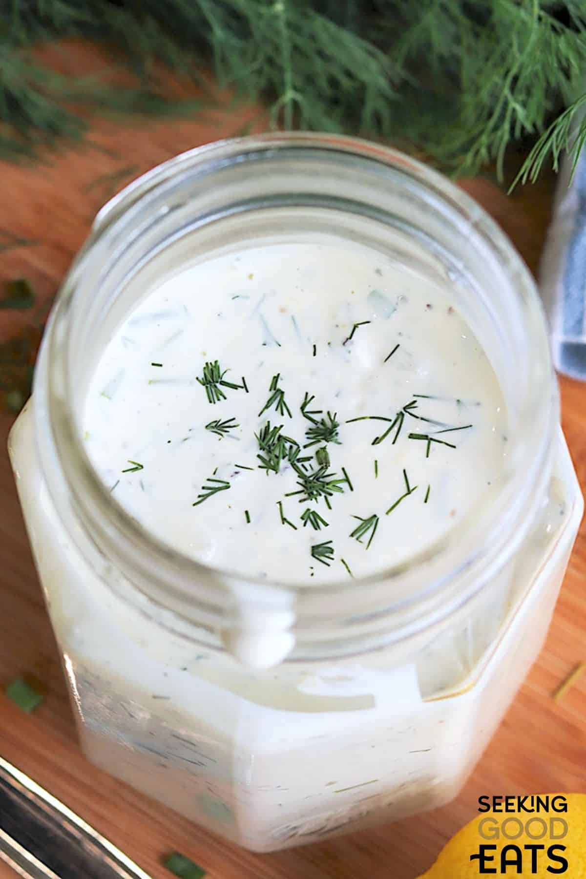 Creamy dill salad dressing with fresh dill sprinkled on top.