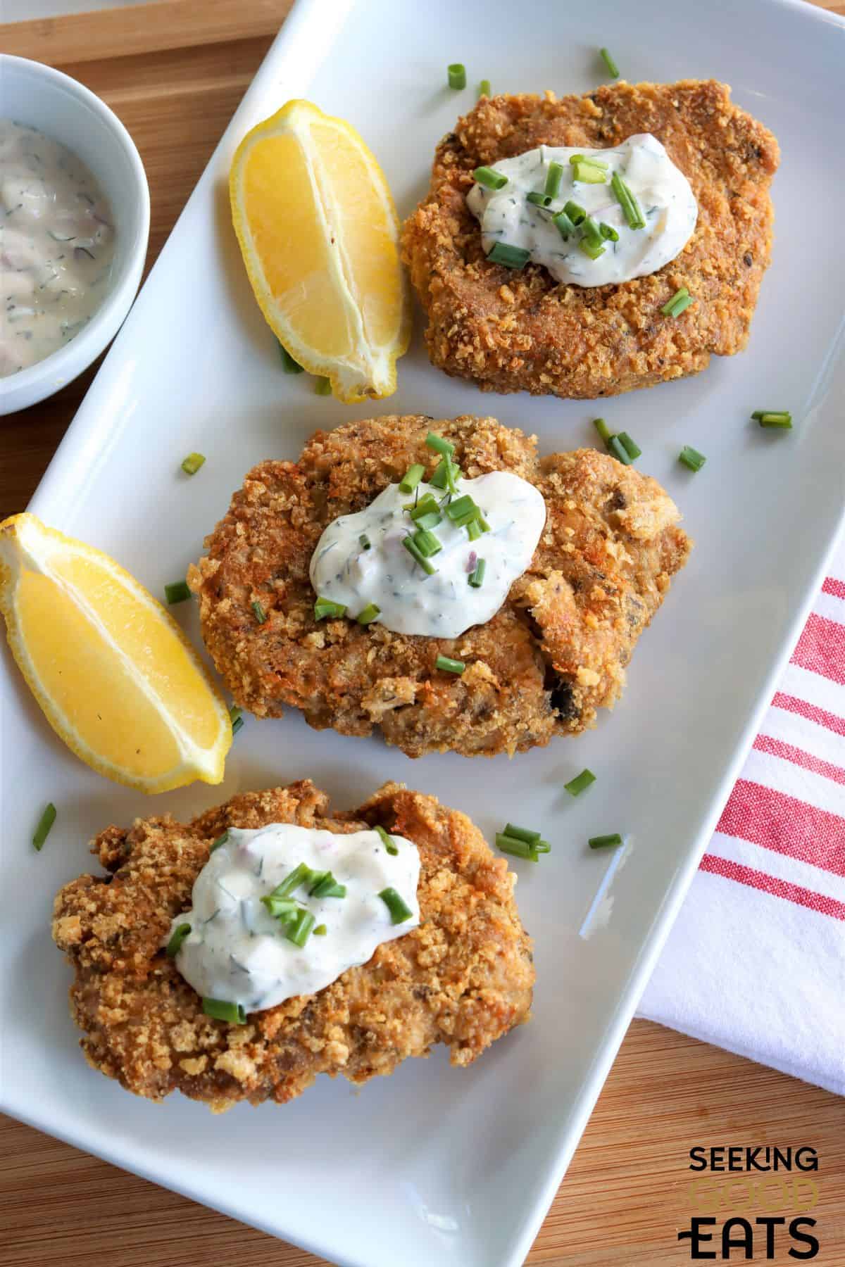 Air fryer salmon patties served on a plate with lemon pieces.