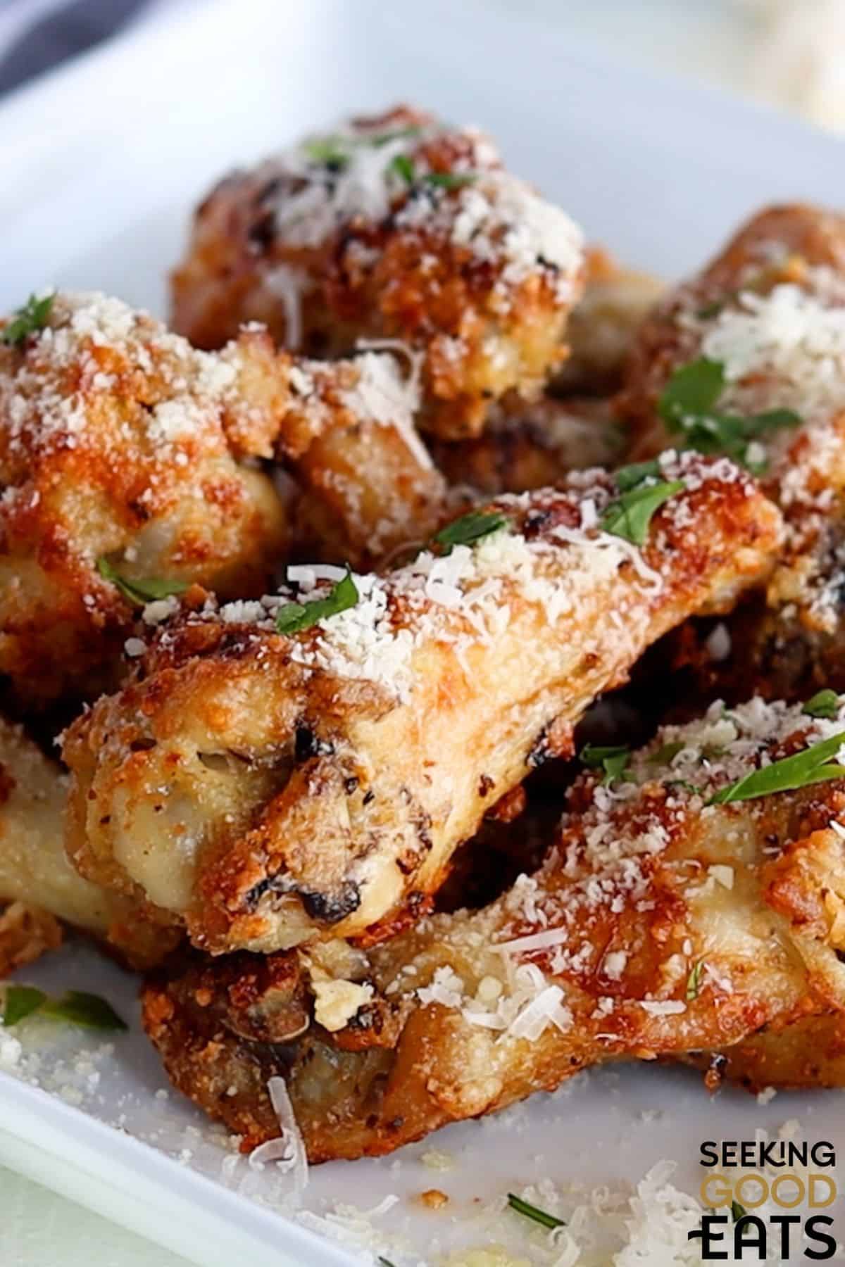 Plate of air fryer garlic parm wings sprinkled with parmesan and parsley.