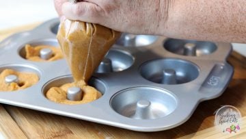 piping donut batter into pan