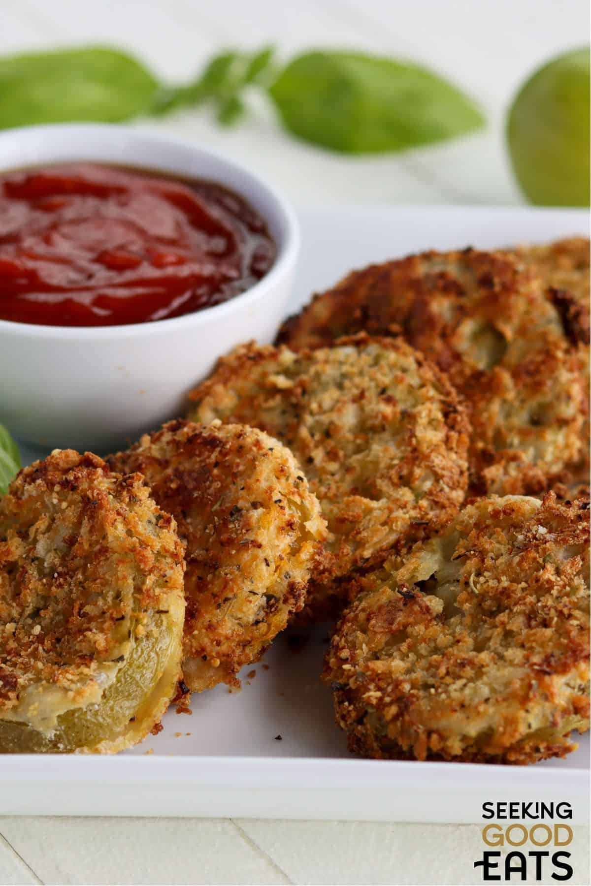 Crunchy air fried green tomatoes on a plate with a dipping sauce.