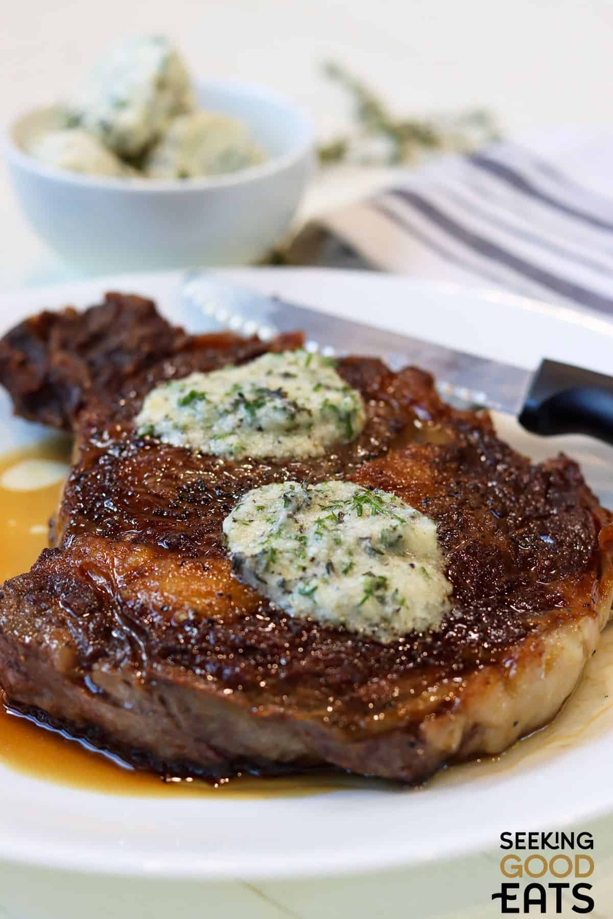 Slices of garlic herb butter melting on hot steak.