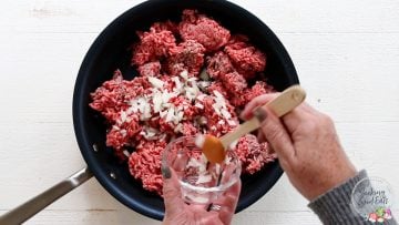 Cooking the ground beef and onion in a skillet until done
