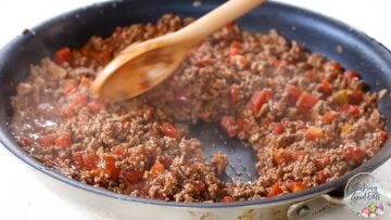 Cooking the seasoned taco meat in a skillet until liquid evaporates