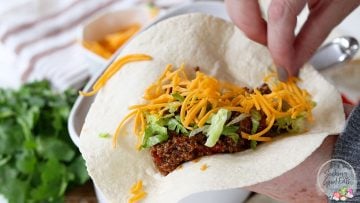 Serving the taco meat on a taco shell with lettuce and cheddar cheese