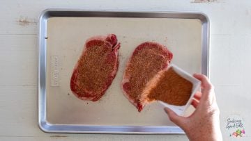 generously sprinkling the chipotle seasoning over the ribeyes