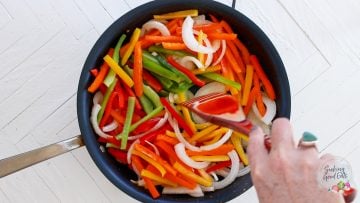 Caramelizing the onions and peppers in a skillet.