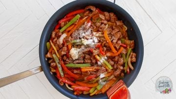 Adding garlic and seasoning to the enchilada filling.