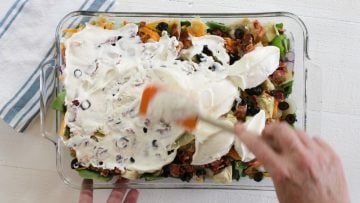 spreading the salad dressing over the layered salad.