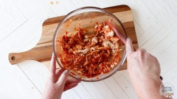 mixing the tinga sauce with the shredded chicken
