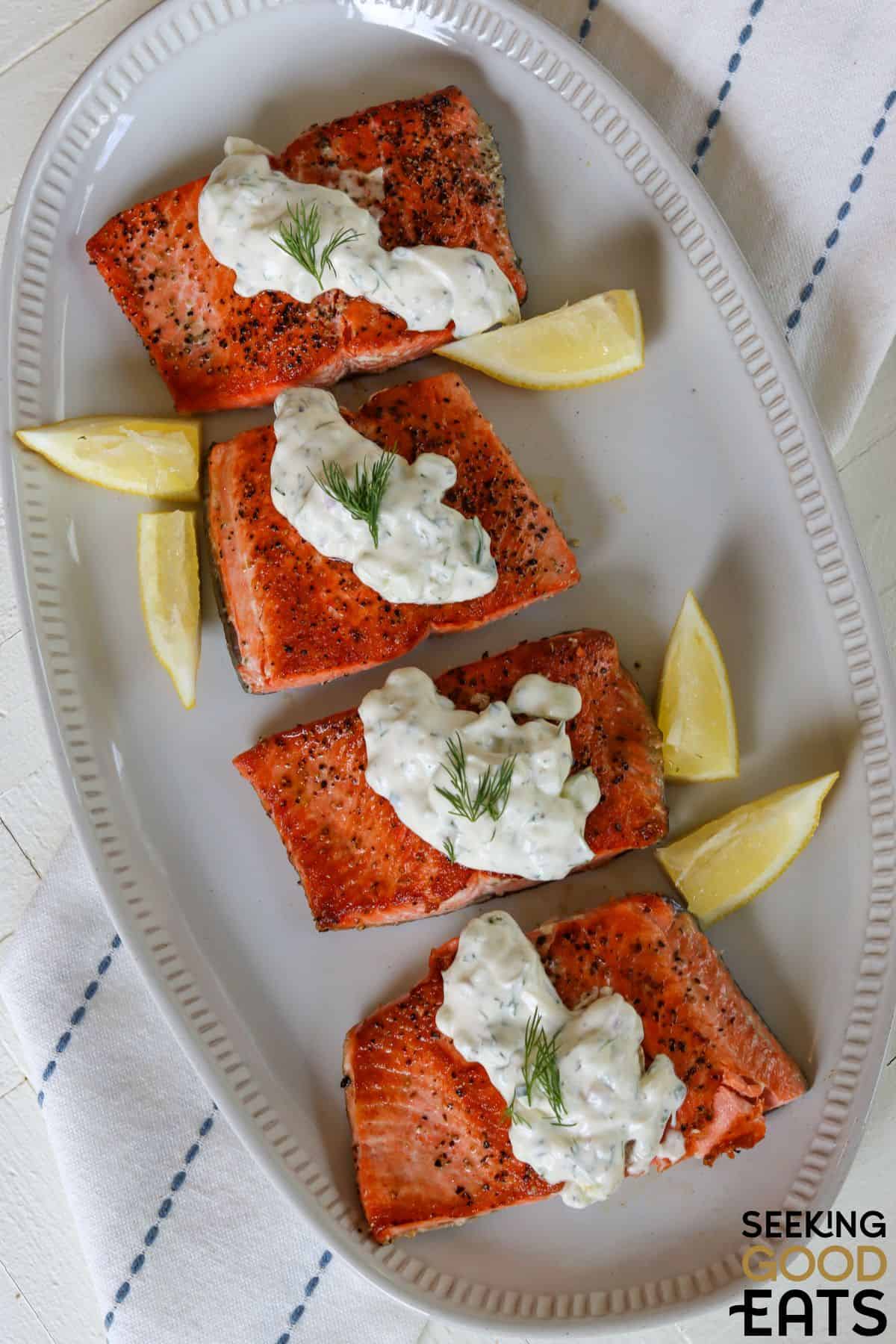 Flaky salmon with creamy dill sauce and lemon wedges.
