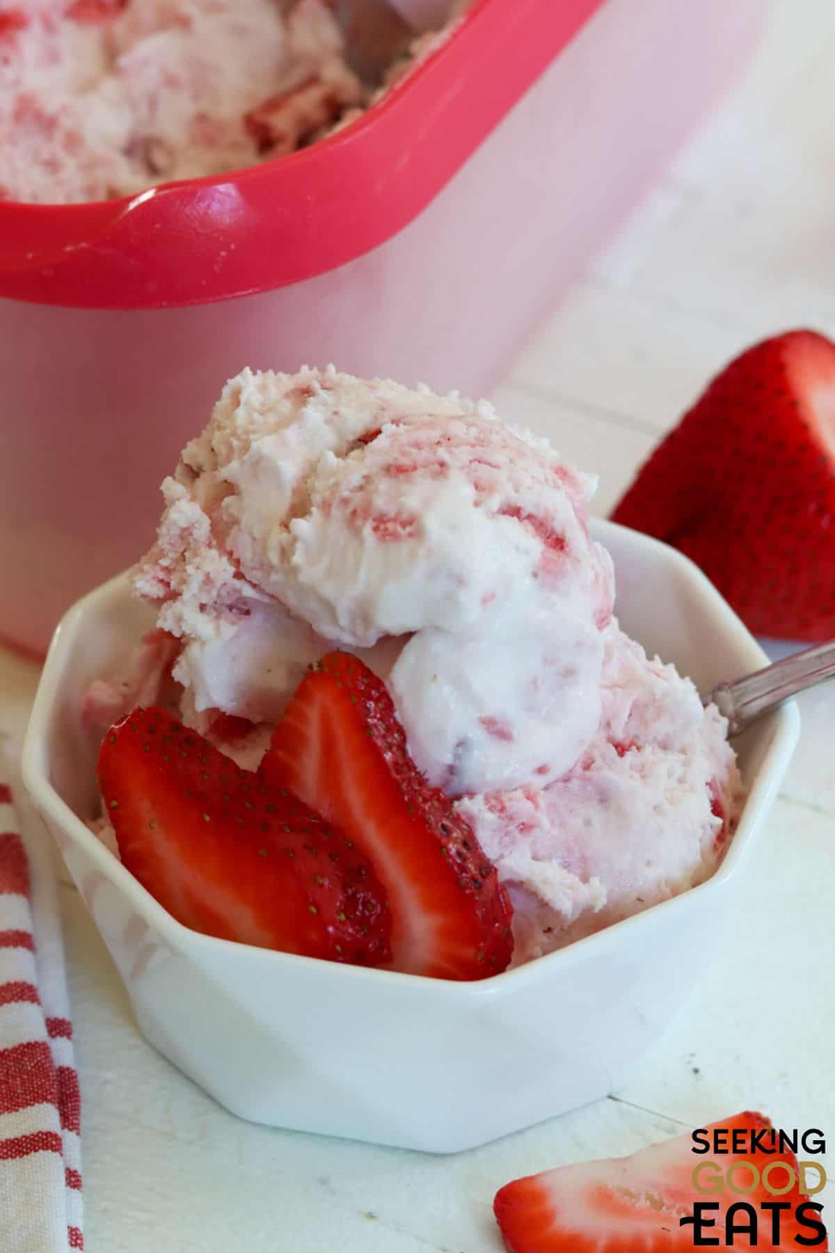 Bowl of homemade strawberry ice cream with fresh strawberry slices.
