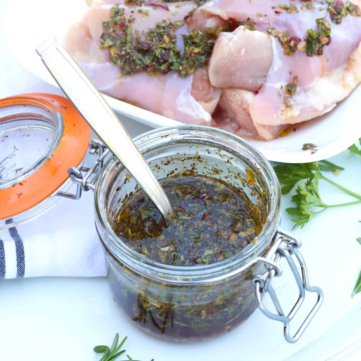 chicken marinade in a lidded glass jar next to chicken thighs in a bowl