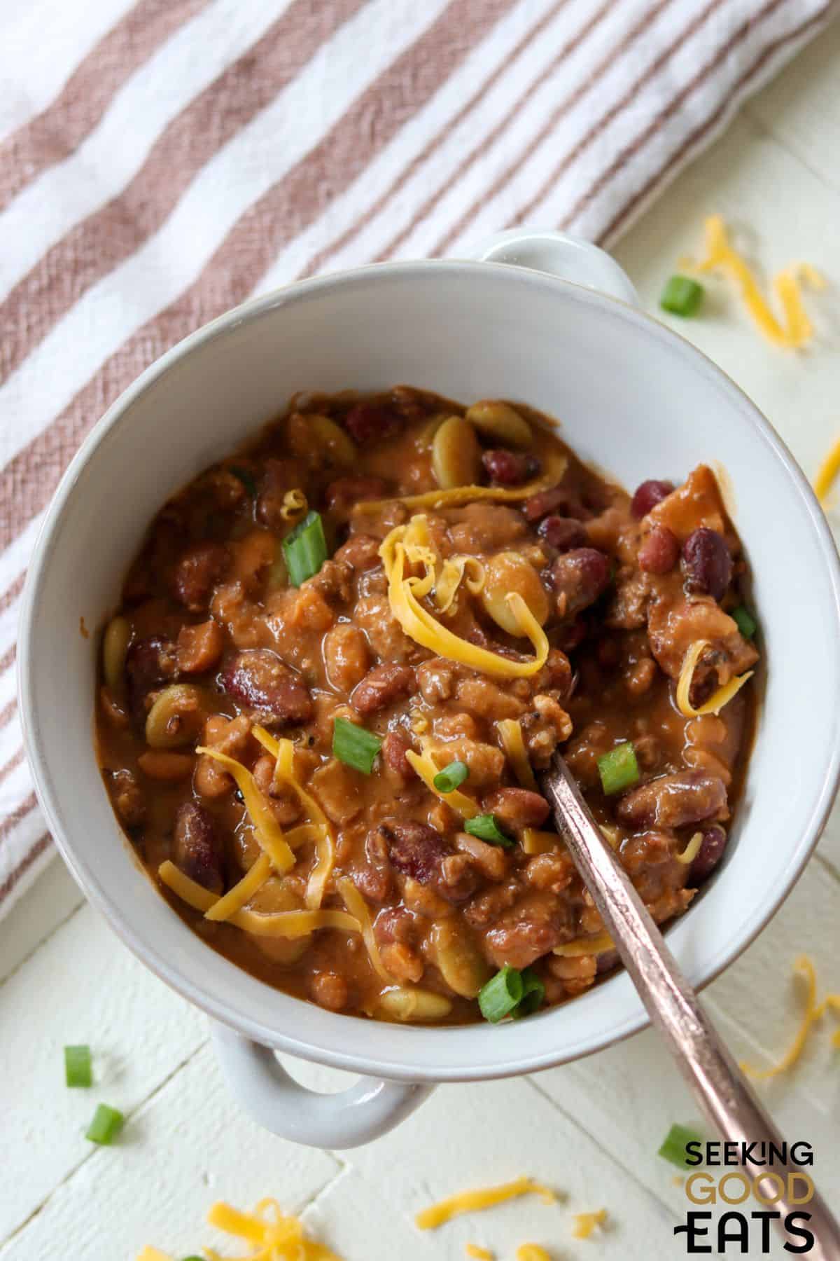 Bowl of ground beef and baked beans served with a spoon.