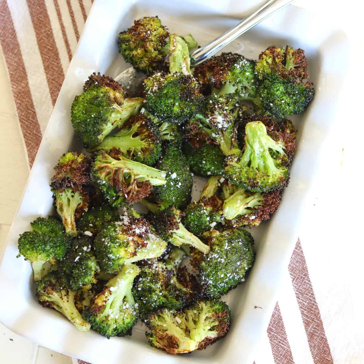 air fryer broccoli served on a white oval platter with a sprinkle of white cheese.