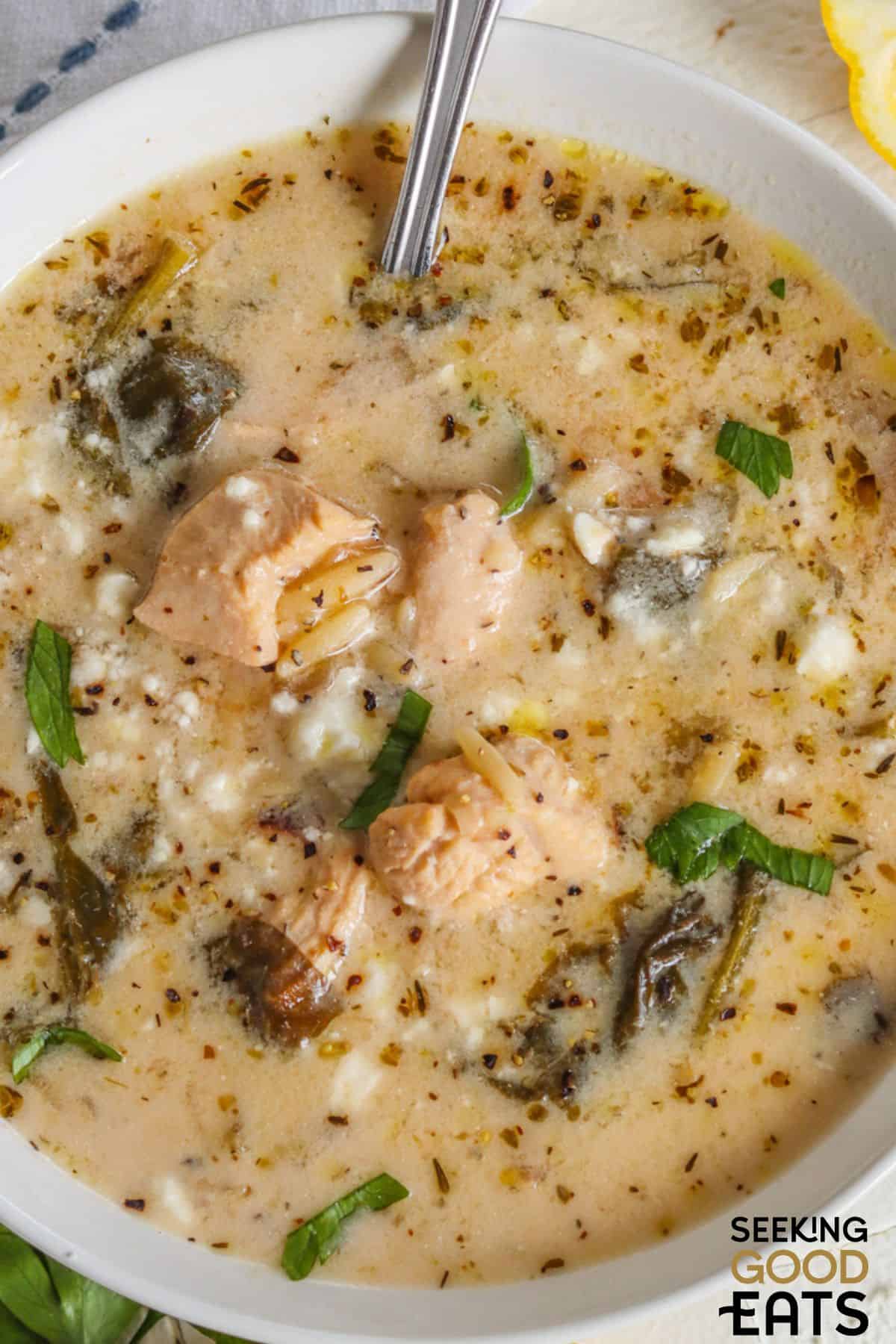 Close-up of Greek chicken soup with lemon and orzo in a bowl with a spoon.