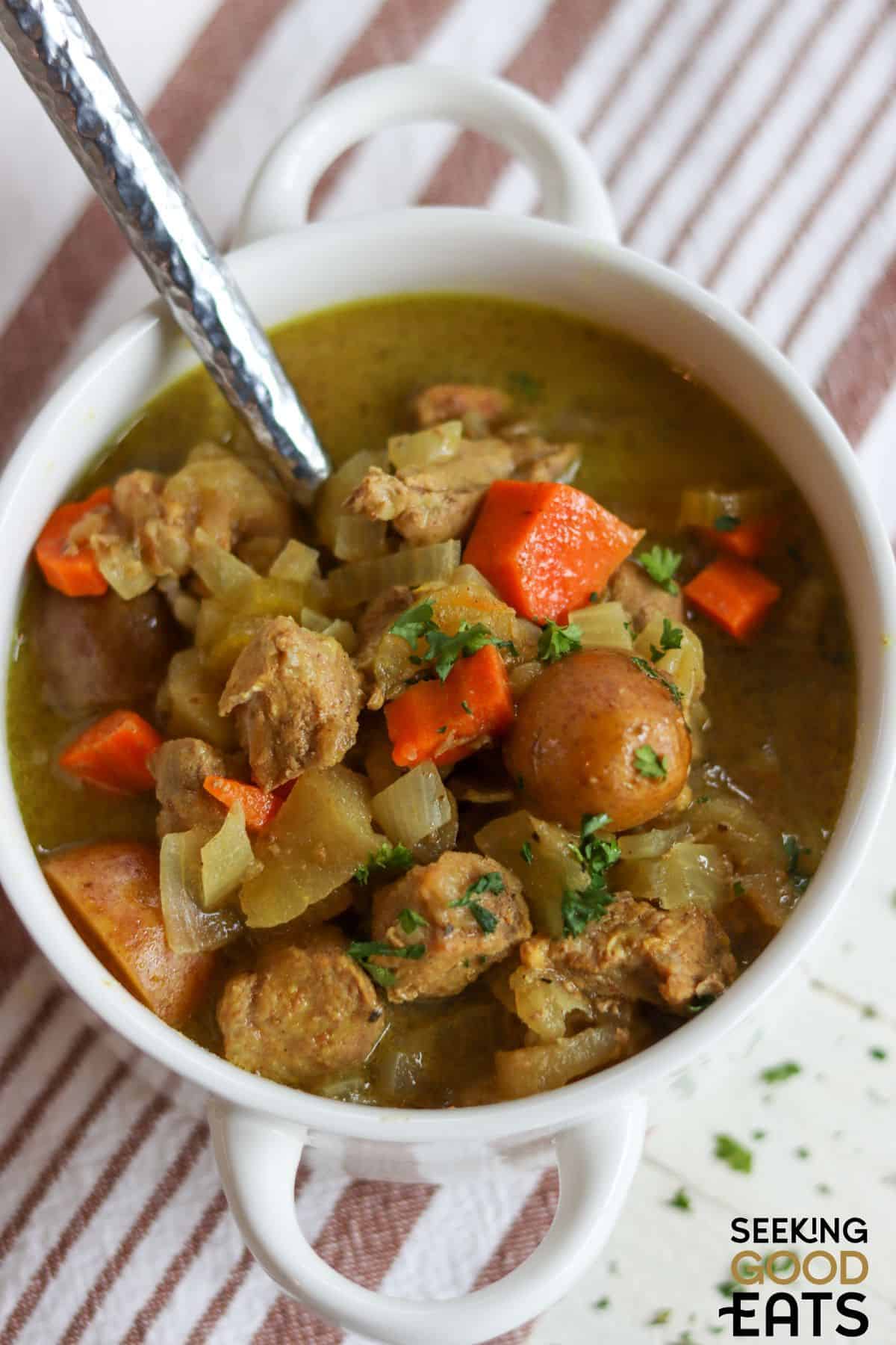 Apple and Cider Crockpot Pork Stew served in a bowl with a spoon.