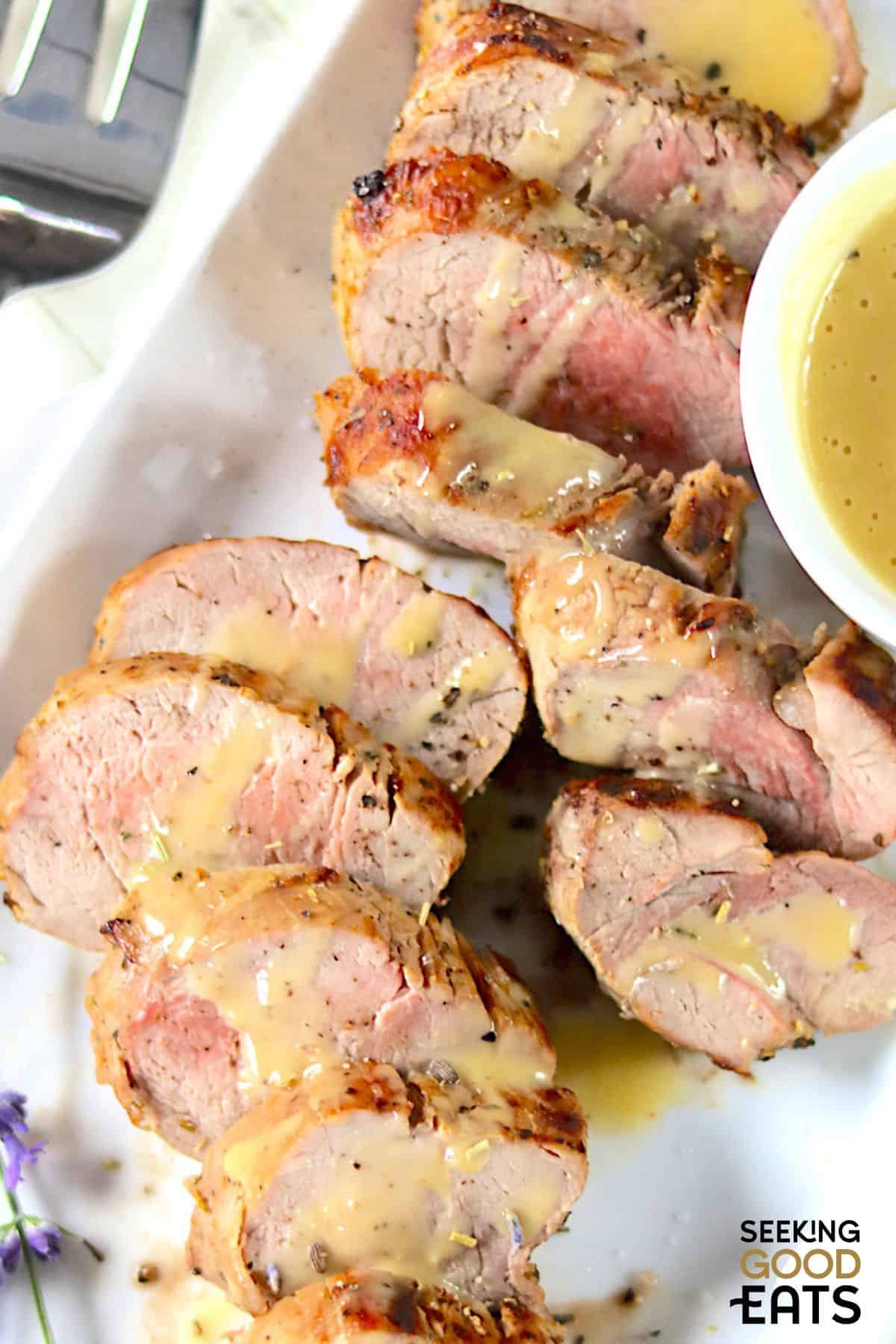 Sliced pork tenderloin with honey Dijon sauce drizzled on top.