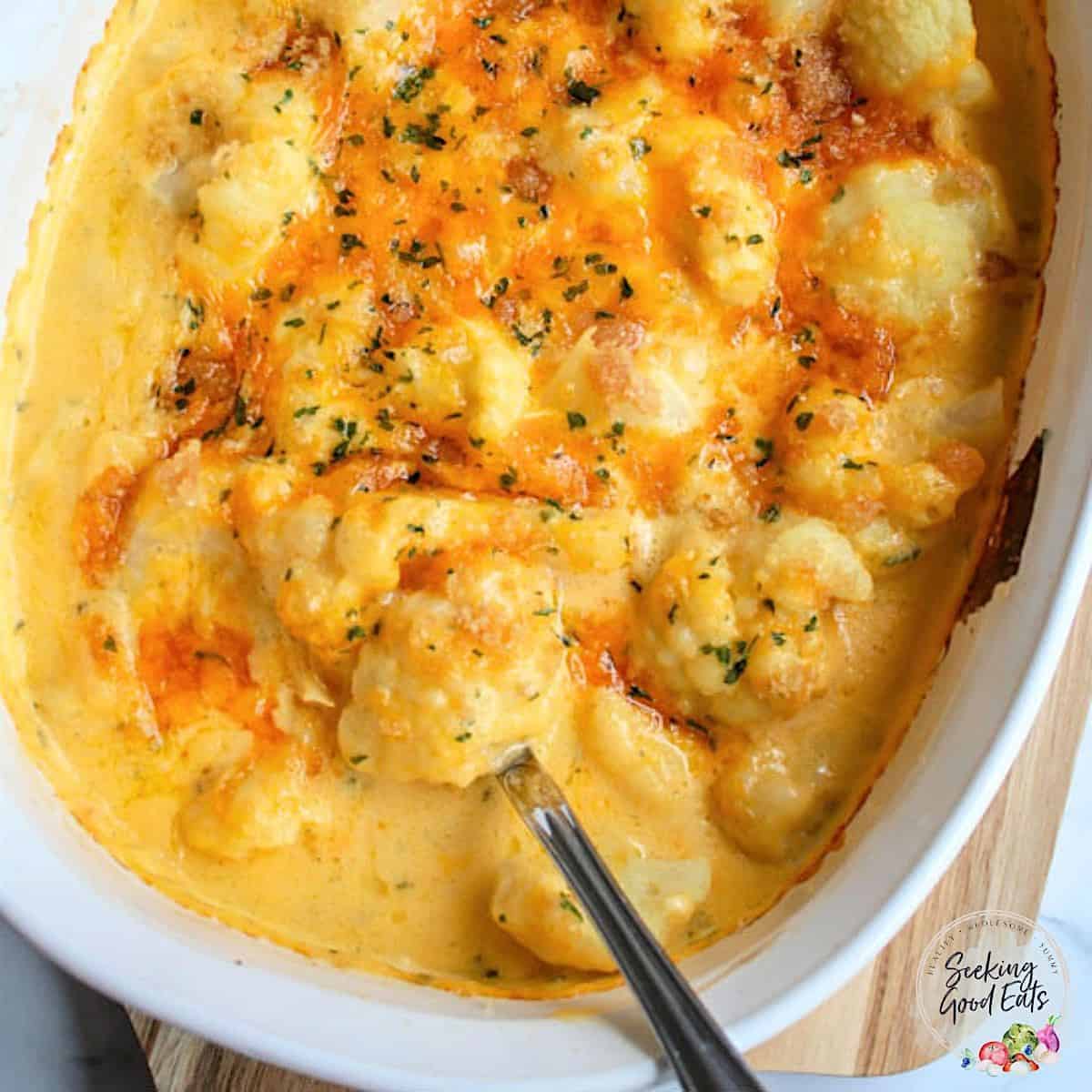 Cauliflower Mac and cheese in a white casserole dish with a serving spoon.