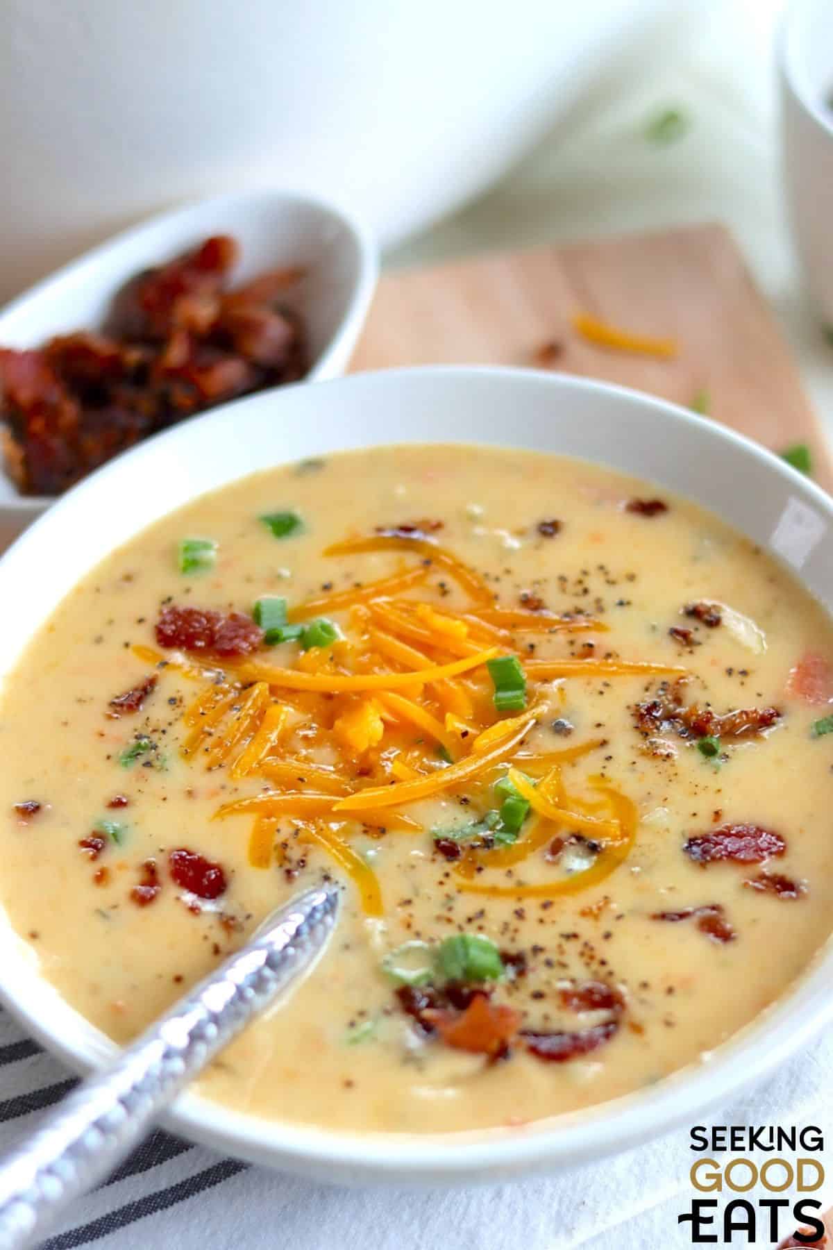 A bowl of creamy potato cheese soup with spoon.