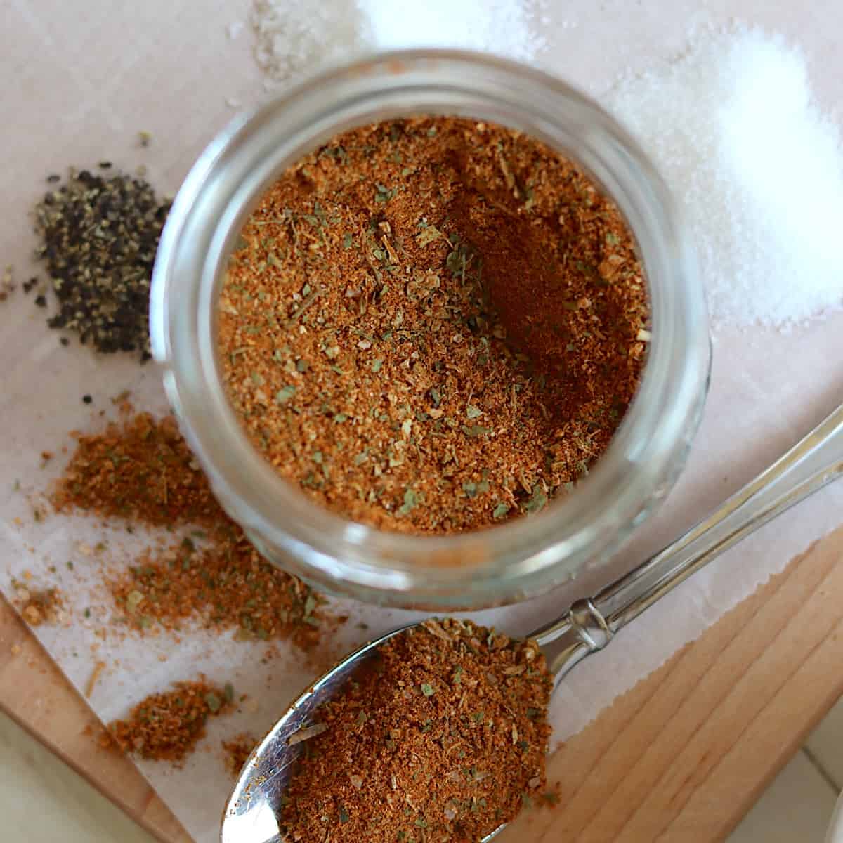 A clear jar of prepared taco seasoning mix.