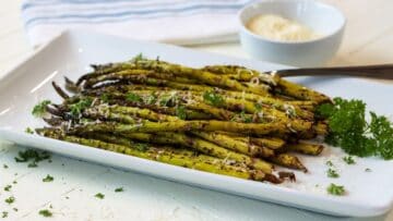 Air fryer roasted asparagus on a white rectangle plate.