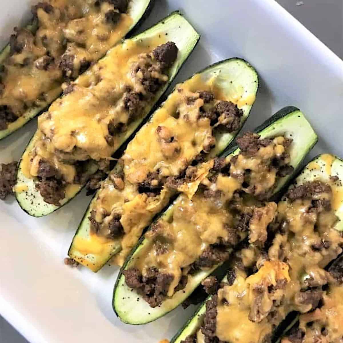 Baked stuffed zucchini taco boats in a white rectangle baking dish.