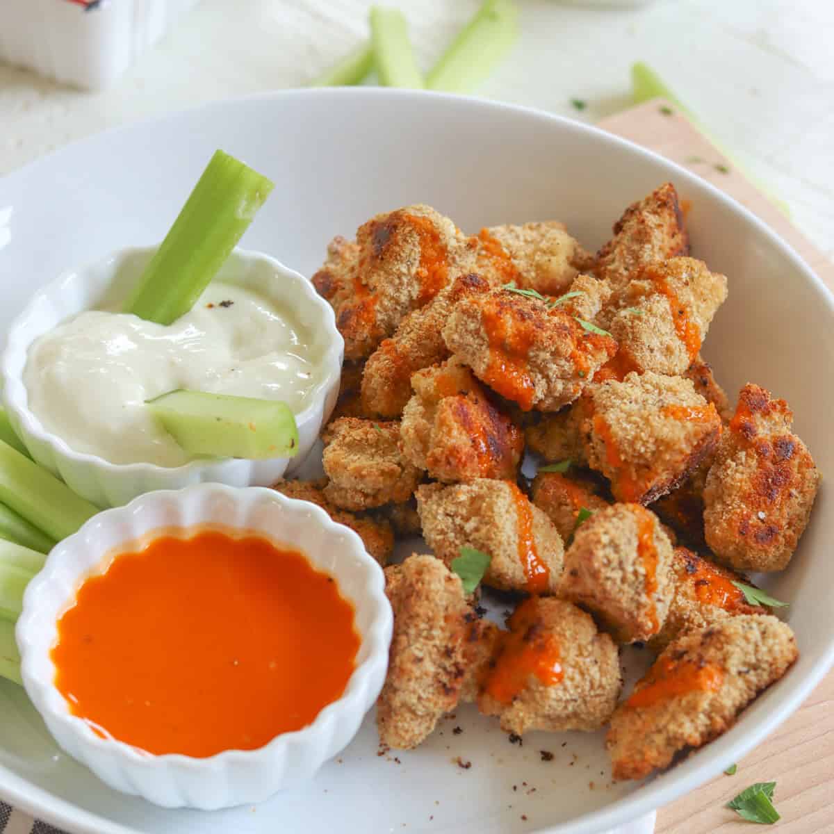 Tofu buffalo wings drizzled with buffalo sauce on a white plate.