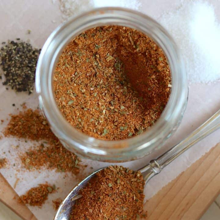 Mixed chicken taco seasoning in an airtight clear glass container.