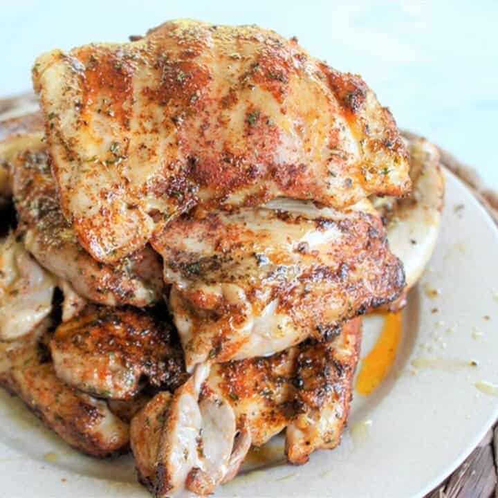 Dry rub on grilled chicken thighs sitting on a white plate.