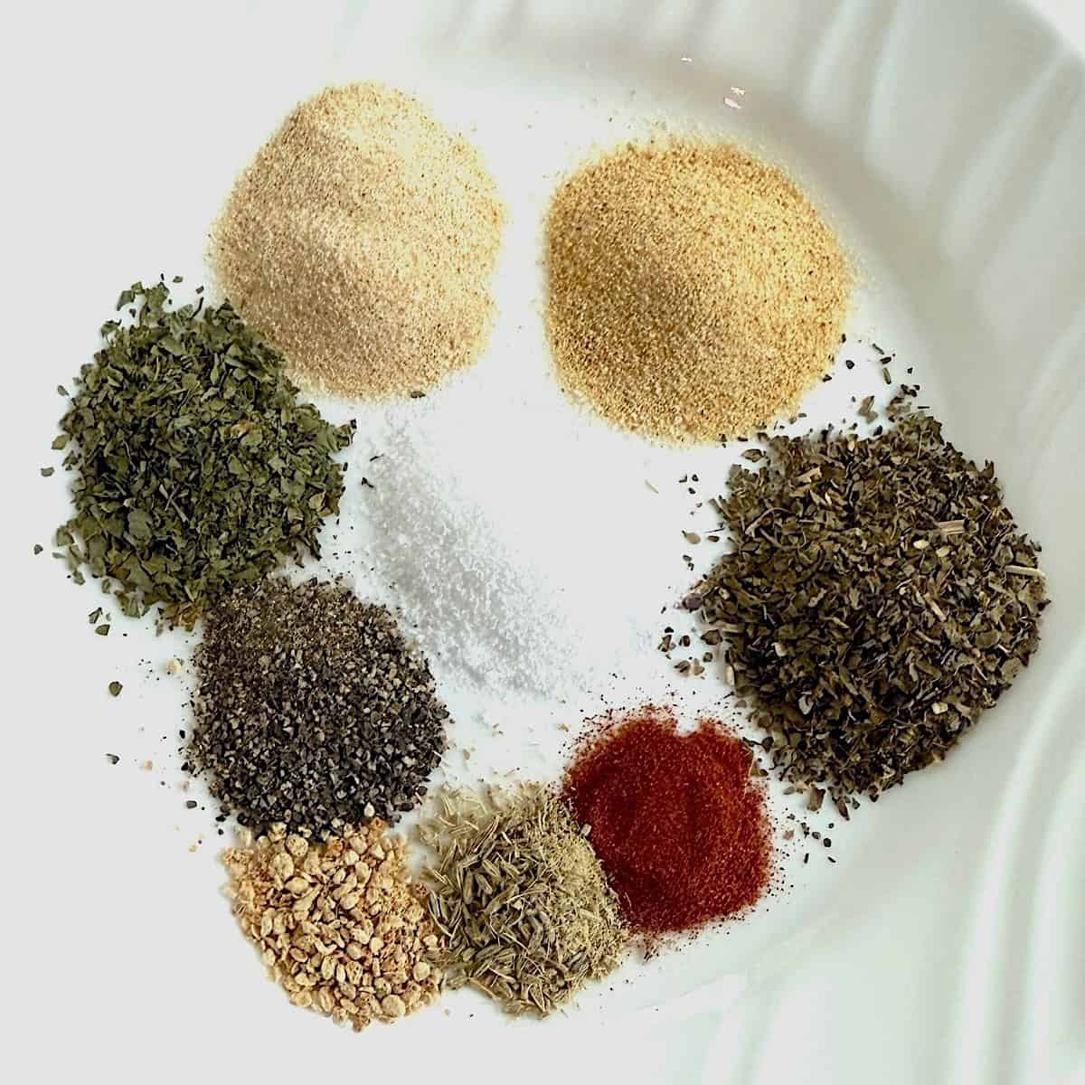 Ingredients needed for making seafood seasoning mix on a white wooden board.