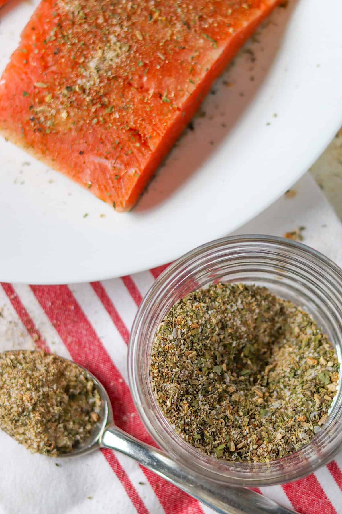 A salmon fillet and seafood seasoning in a clear glass container.