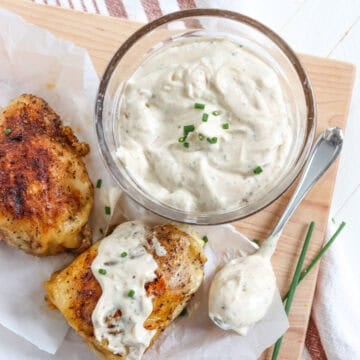 White bbq sauce in a clear glass bowl and smothered over grill chicken.