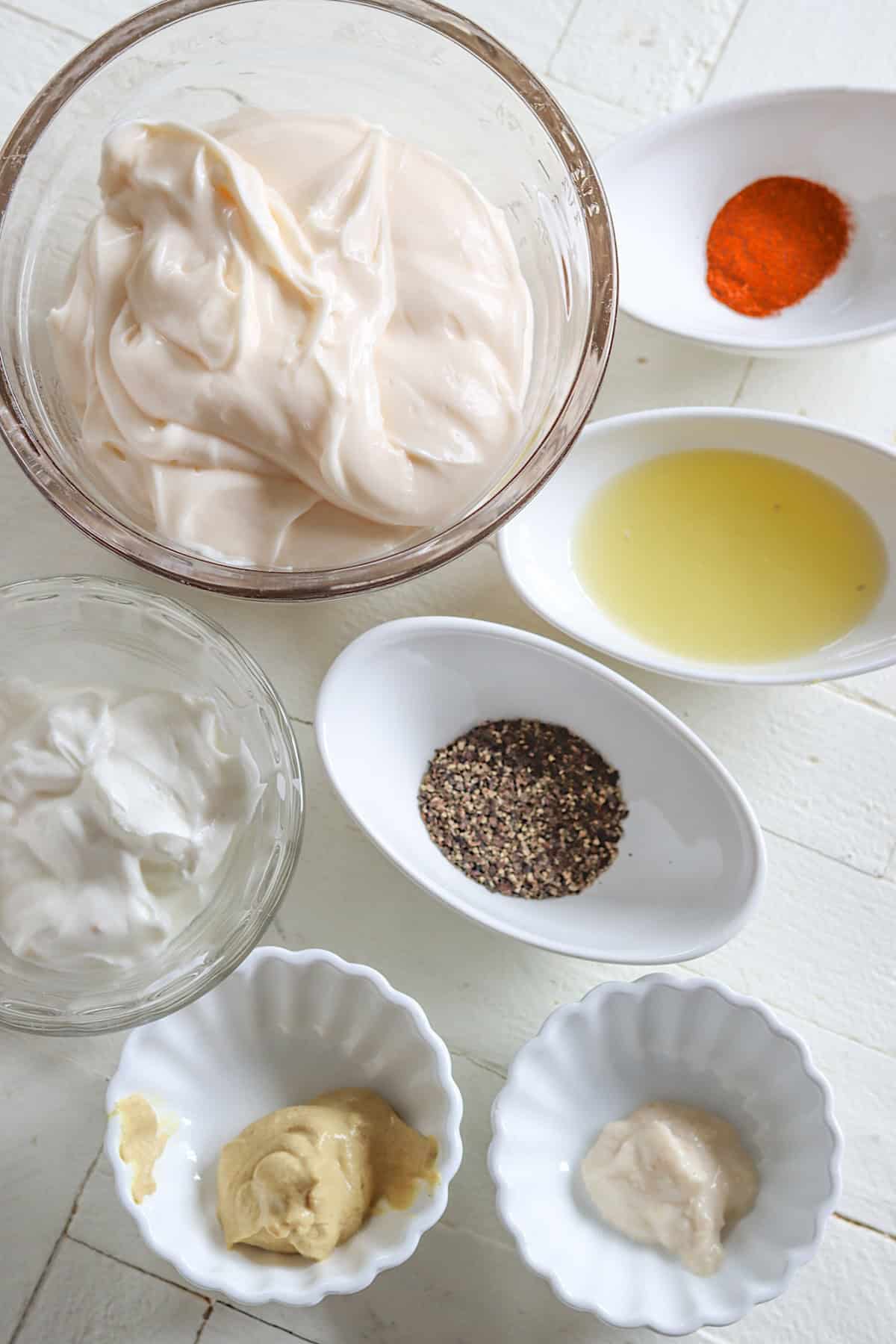 Ingredients needed for making white bbq sauce on a white wooden board.