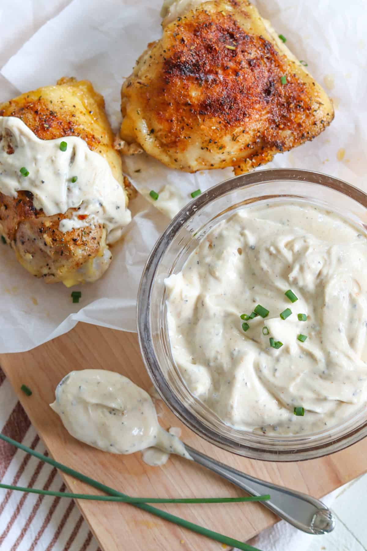 Two pieces of chicken and a clear bowl of white bbq sauce.