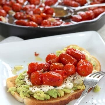 Cherry tomato confit on avocado toast with ricotta cheese.