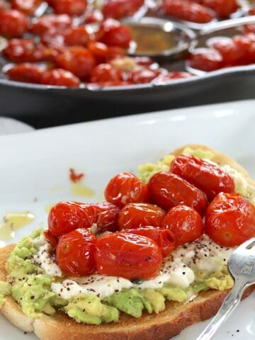Cherry tomato confit on avocado toast with ricotta cheese.