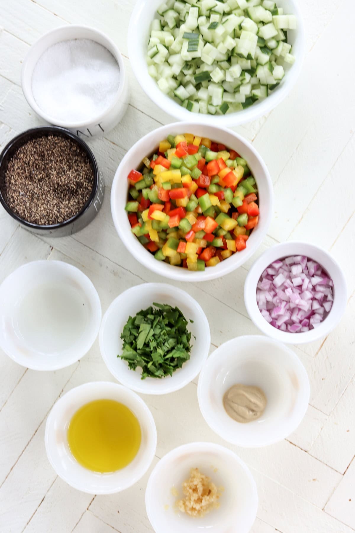 Ingredients needed for making cucumber bell pepper salad on a white wooded board.