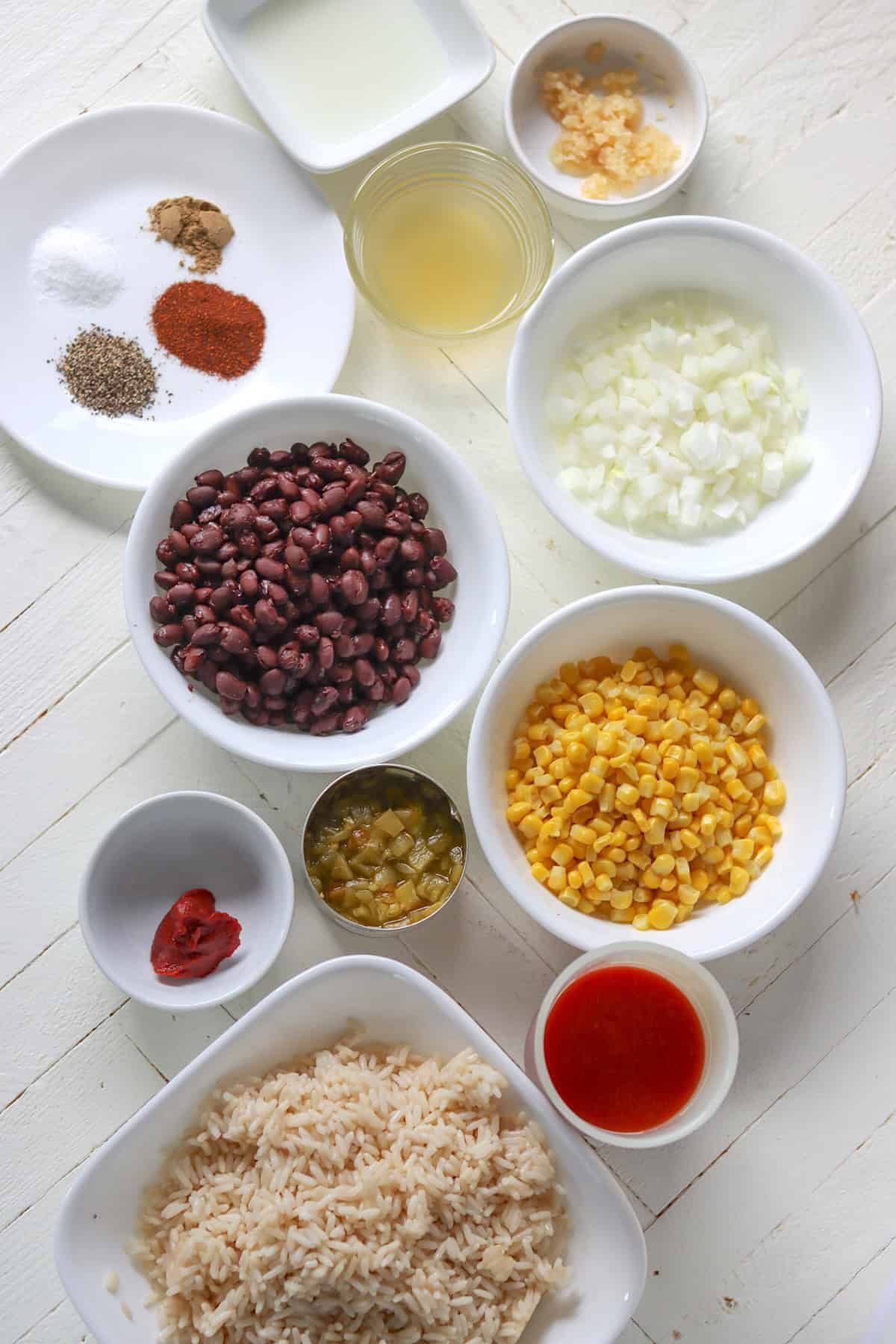 Ingredients needed for making Mexican fried rice on a white wooden board.