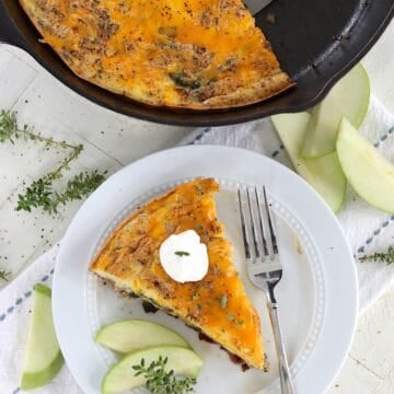 a wedge slice of baked egg frittata with apples and cheddar cheese.