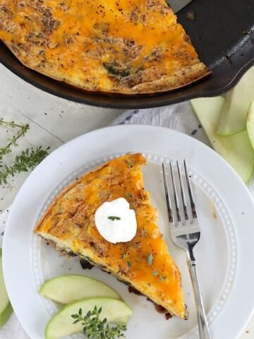 a wedge slice of baked egg frittata with apples and cheddar cheese.