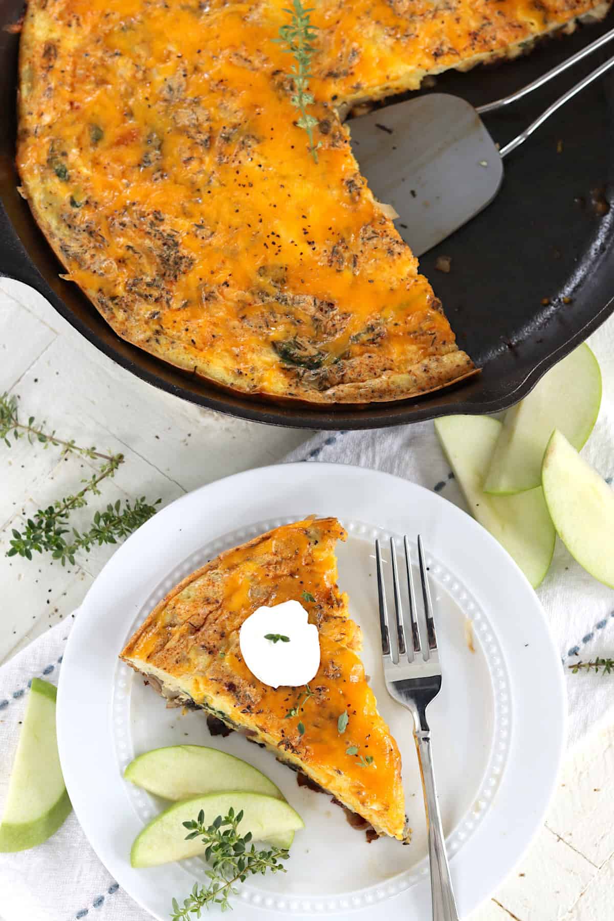 An oven safe skillet with baked apple cheddar cheese frittata.