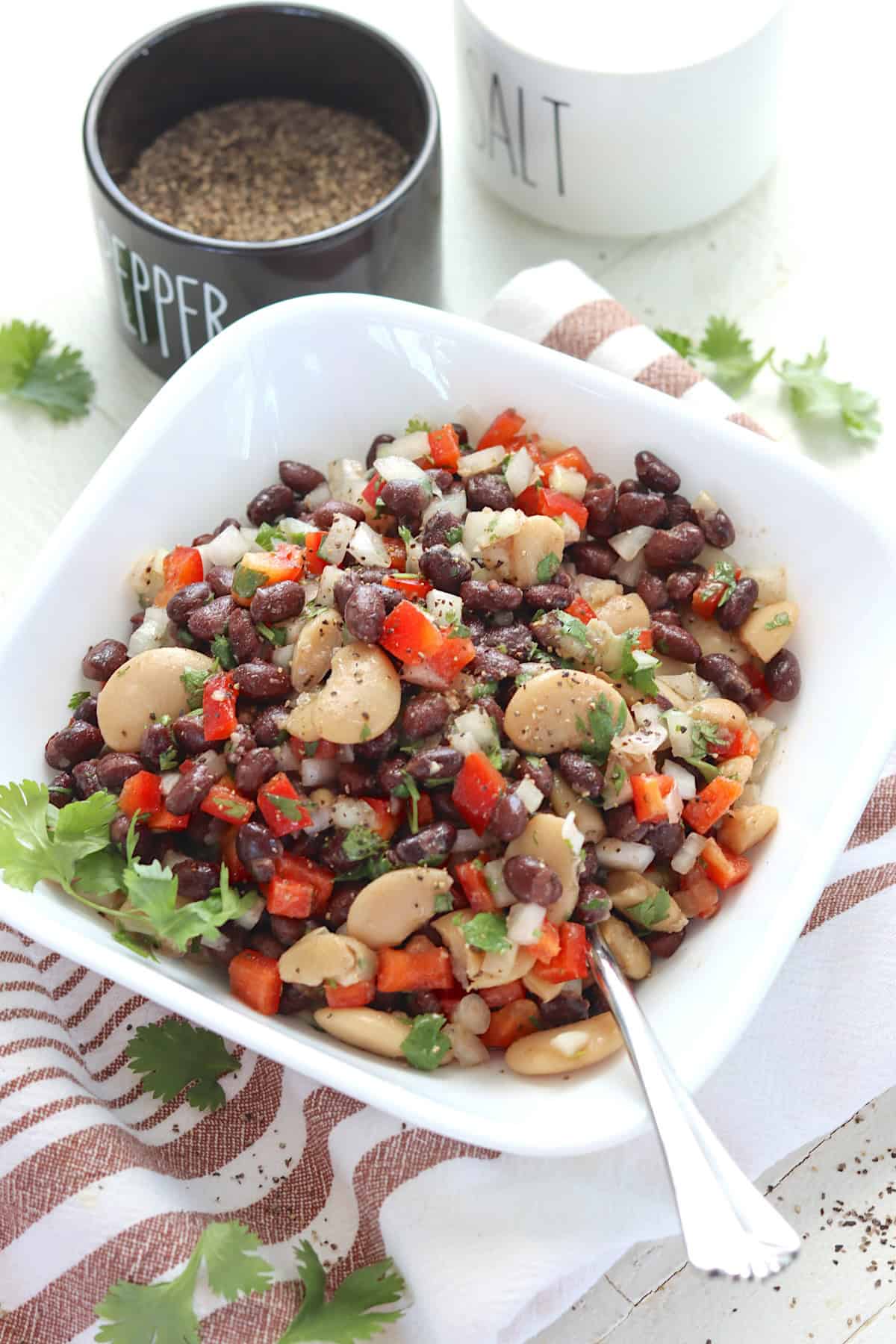 Black bean salad salad recipe with butter beans and bell peppers in a square white bowl.