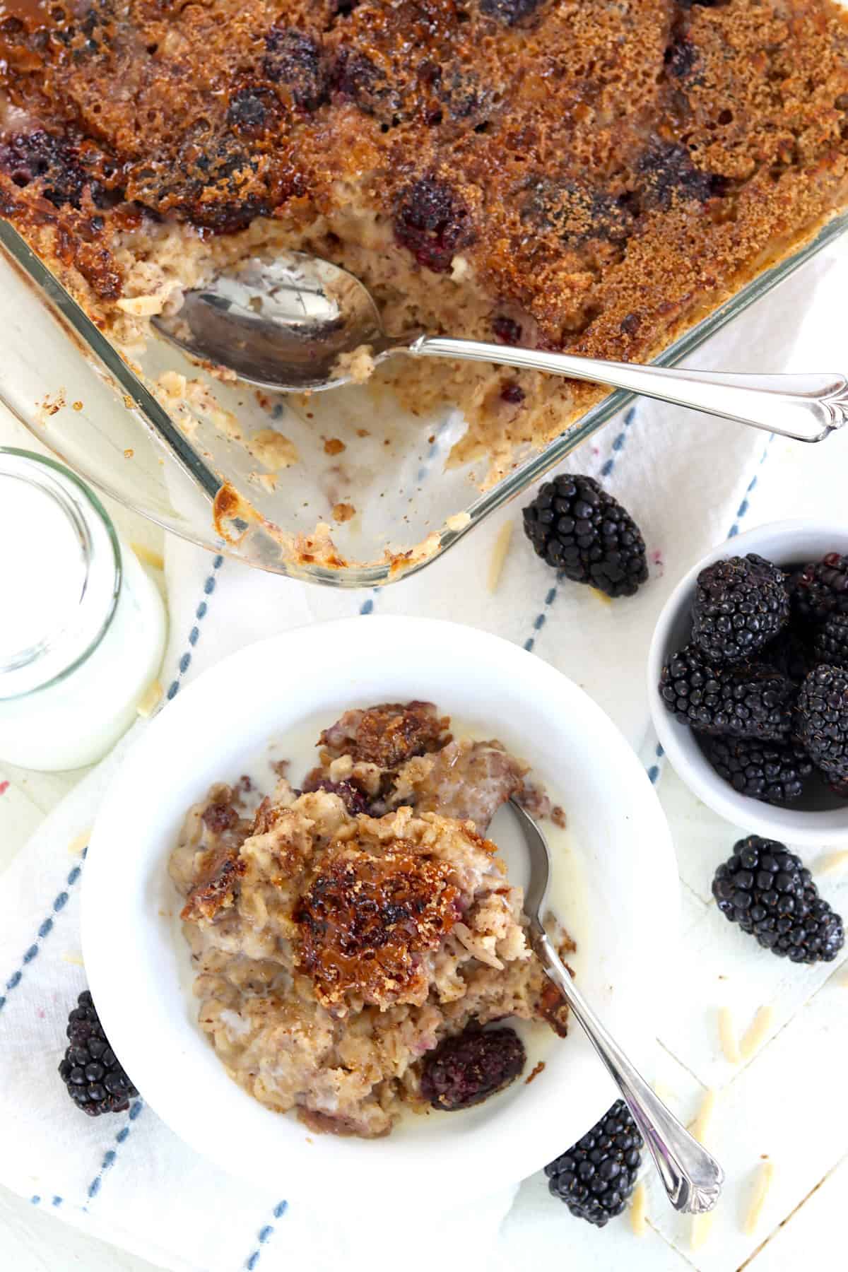 A baking dish and a white bowl of blackberry baked oatmeal.
