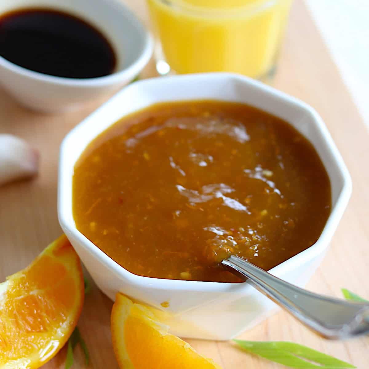 Recipe for orange sauce for chicken in a small white bowl with a spoon.