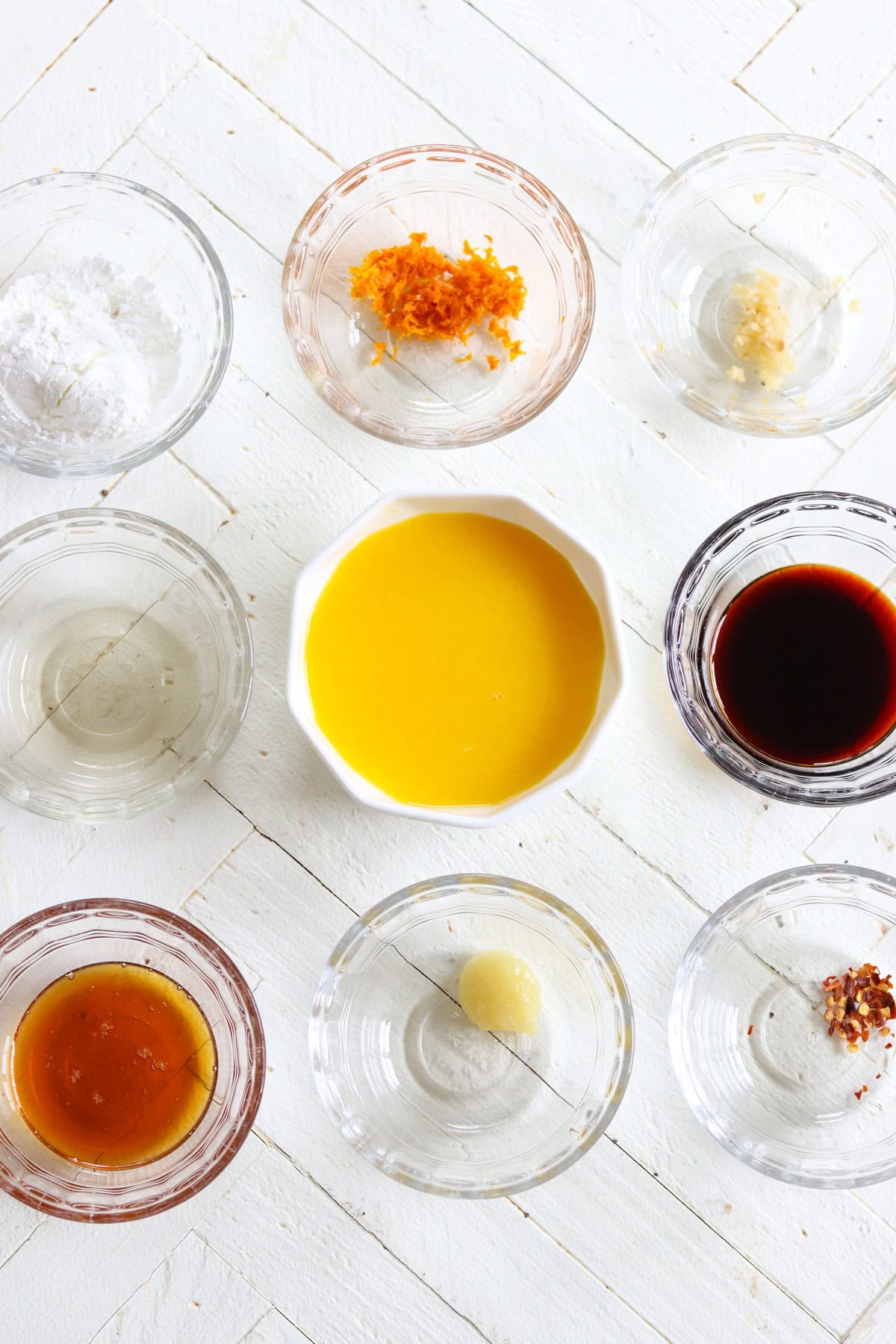 Ingredients needed for making orange sauce for chicken recipe on a white wooded board.