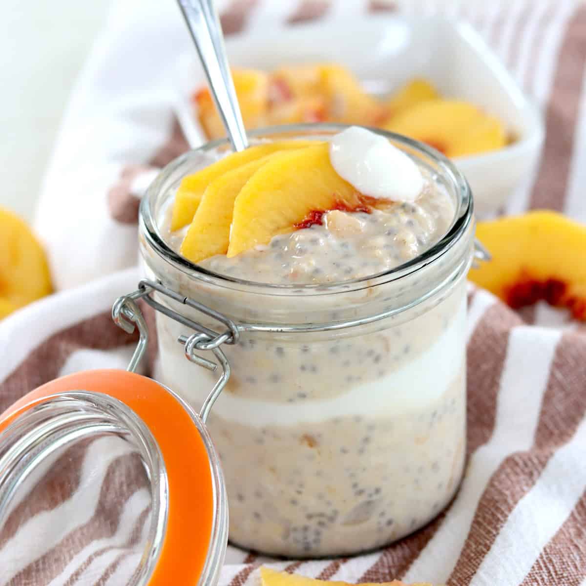 Layered peach overnight oats with vanilla yogurt and fresh sliced peaches.