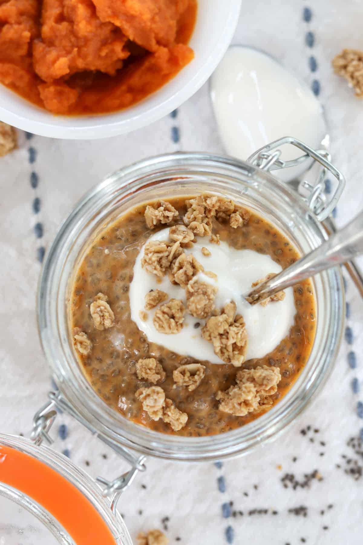 Pumpkin chia pudding in a glass jar with yogurt and granola.