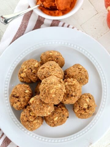 A white plate with pumpkin protein balls piled on top of each other.